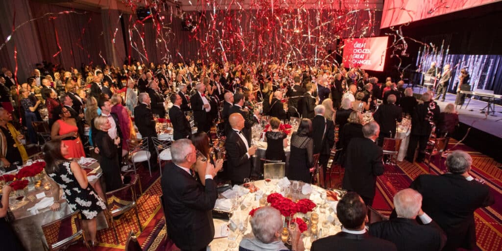 A black-tie fundraising celebration with confetti falling on the multiple guests in a ballroom dinner setting.