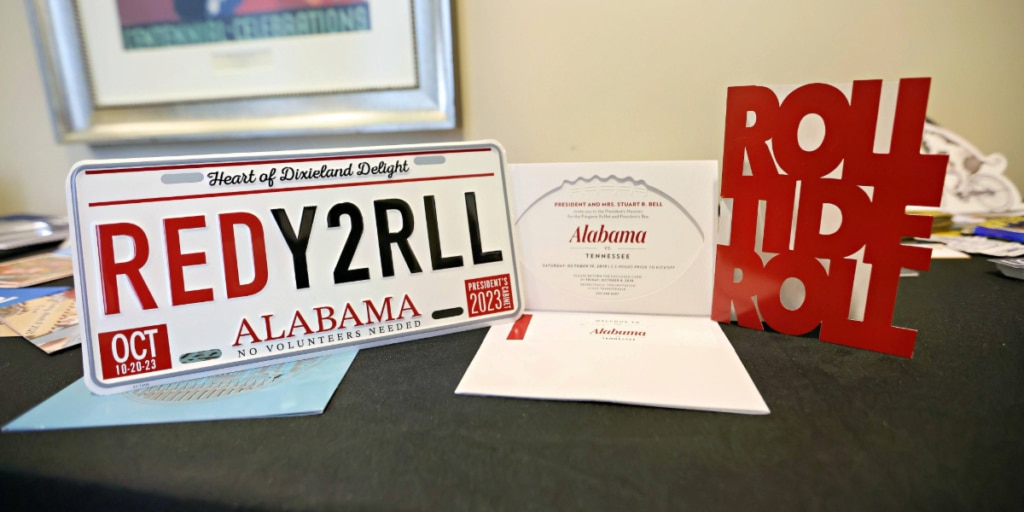 Examples of SWAG for a University of Alabama event. A specialised license plate, Roll Tide Roll cutout, and an invitation.